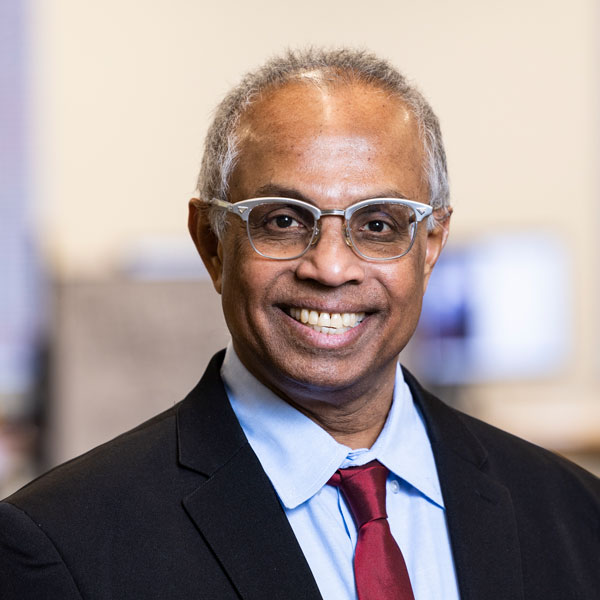 Professor Duminda Wijesekera of the CYSE department at Mason, wears a light-blue shirt, red tie, dark suit, and glasses in his profile