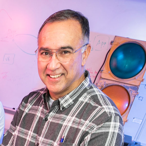 CYSE associate professor Paulo Costa wears a plaid shirt and glasses in his profile for the Department of Cyber Security Engineering at Mason