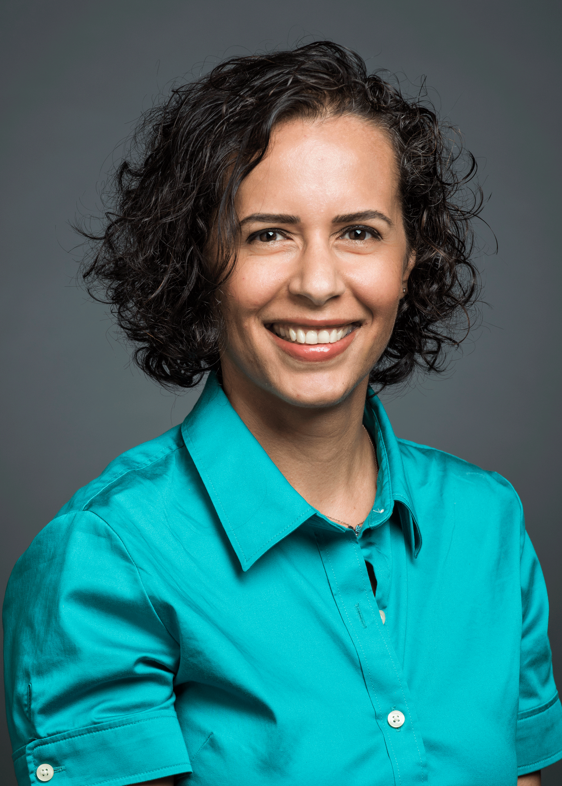 Dr. Özlem Uzuner wears a teal shirt and smiles in her faculty profile for the Department of Information Sciences and Technology.