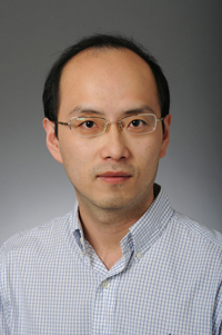 Mason associate professor Xu Jie wears a light-blue shirt, glasses, and has balding hair in his profile