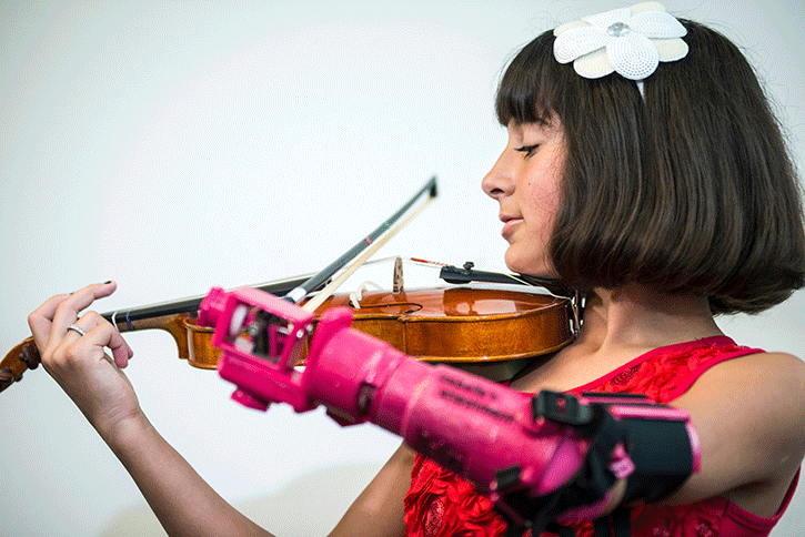 Young violinist demonstrates prosthetic arm that bioengineering students designed.