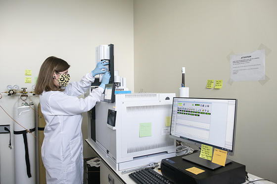 Kirin Furst standing in front of a mass spectrometer setting the controls. 