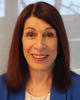 Ariela Sofer wears a blue blazer and has dark, red hair in her faculty profile