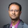 Mason associate professor Rajesh Ganesan wears a gray suit, tie, and glasses