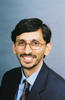 Mason professor Syed Abbas wears a navy-blue suit, dark tie, and glasses and has dark hair in his profile